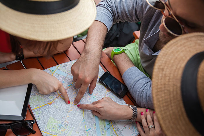 three friends pointing at a map