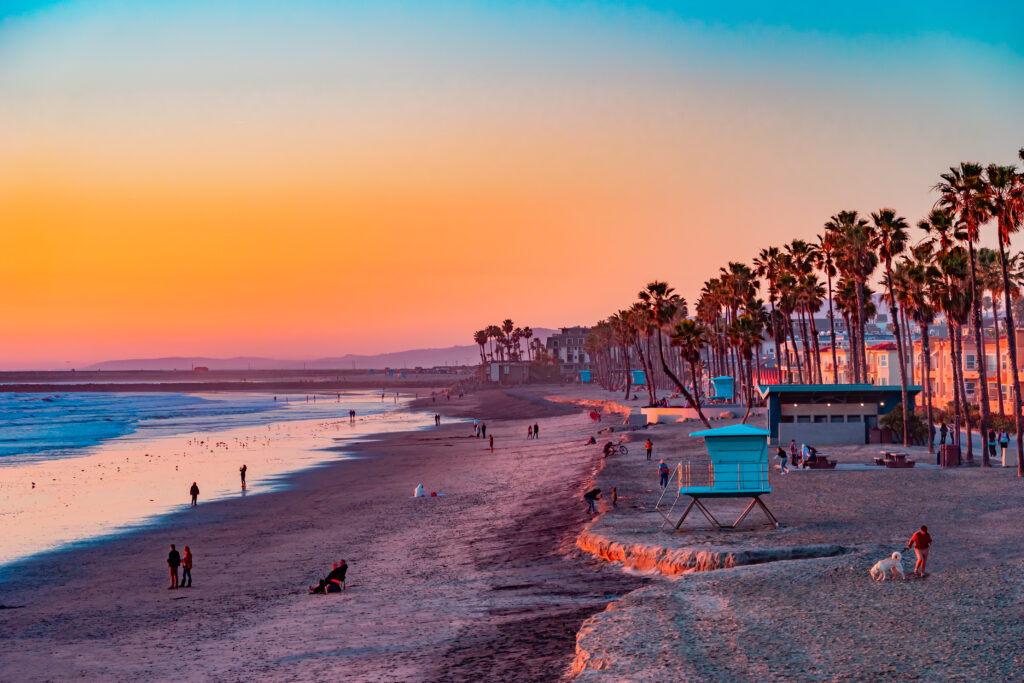 People sit and stroll at sunset on the beach in Oceanside, California. This is next to Carlsbad and San Diego.